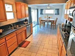 This large galley kitchen has basket weave tile flooring, dark g